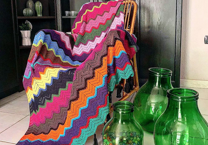Coperta all'uncinetto con motivi a zigzag in molti colori, posata su una sedia
