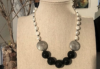 Collana con elementi rotondi bianchi neri e grigio argento su busto